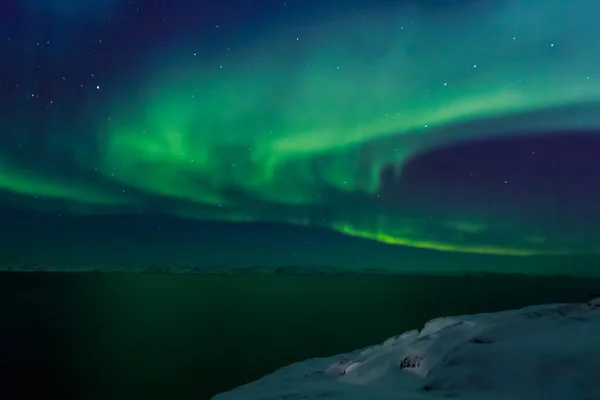 Spiral green Northern lights shining over the fjord with mountai — Stock Photo, Image