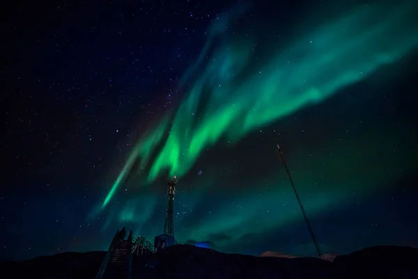 Ondas verdes de Aurora Boreal con estrellas brillantes sobre el monte —  Fotos de Stock