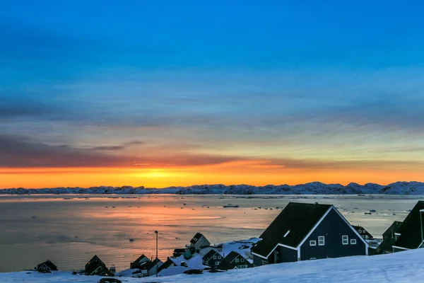 Inuit huizen op het fjord met zonsondergang uitzicht over de bergen, N — Stockfoto