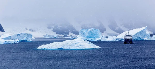 Snowfall and cruise ship among blue icebergs in Port Charcot, Bo — Stock Photo, Image