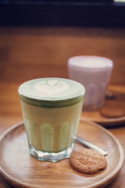 Ahşap masa arkasında kibrit yeşil çay latte sanat.