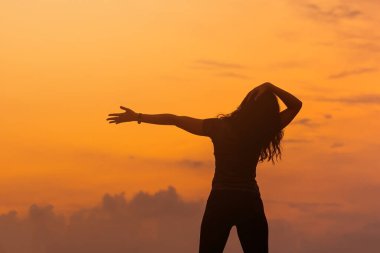 Kadın, güzel bir gün batımına karşı ısınma egzersizi yapıyor..