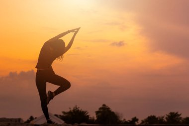 Kadın, güzel bir gün batımına karşı ısınma egzersizi yapıyor..