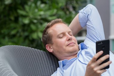 Gündelik tarzı olan genç, mutlu, beyaz bir adam bilgisayarda çalışıyor..