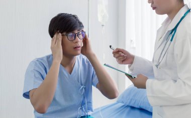 Genç Asyalı hasta doktorla tanışıyor, baş ağrısı, depresyon, sağlık konsepti....