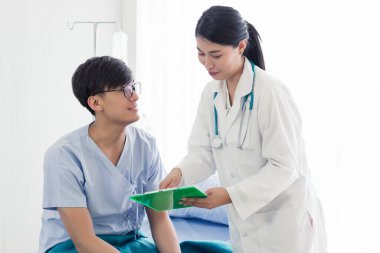 Beyaz önlüklü güzel bayan doktor hastasına danışıyor, sağlık kontrolü sonuçlarını gösteriyor..