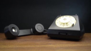 Ahşap masada klasik siyah arama telefonu.