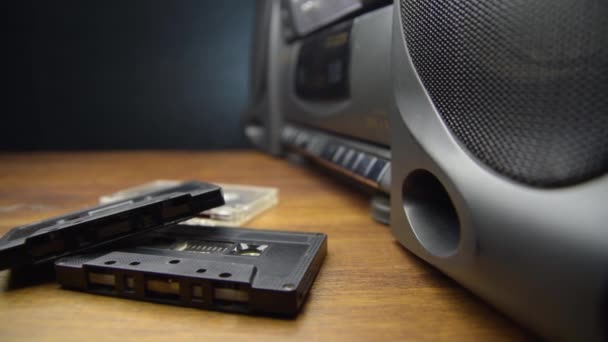 Casetes de audio antiguos y un reproductor en una mesa de madera — Vídeo de stock