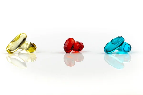 A mix of multicolored medical soft gel capsules on a white background - medical supplements , red, yellow, blue