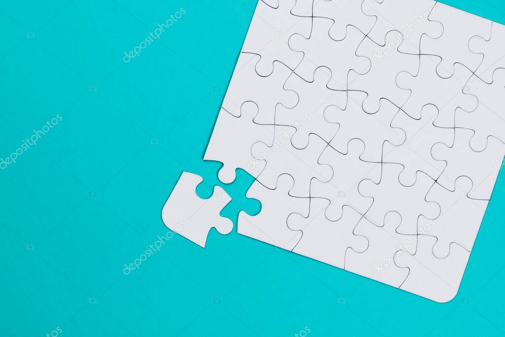 Close-up white jigsaw puzzle with a missing piece - blue background