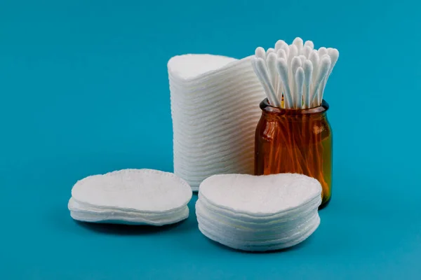 Q-tips, cotton swabs, cotton pads, isolated on bright blue background. Amber bottle