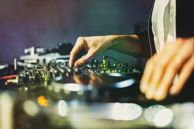 DJ bir disko kulübünde müzik çalıyor. Elleri yakın ve bokeh ışıkları yanıyor.