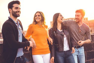 Bir grup modaya uygun genç dışarıda duvarın önünde sohbet ediyorlar. Öğrenciler birlikte eğleniyor. Gülümseyen sarışın kıza odaklan. Yaşam tarzı kavramı.