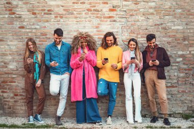 Eski bir duvara karşı akıllı telefon kullanan çok ırklı arkadaşlar cep telefonu bağımlısı gençler her zaman bağlı olan teknoloji konsepti. Sosyal medyayı kullanarak. Filtrelenmiş resim