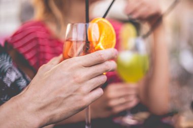 Bir grup arkadaş sahildeki büfede kokteyllerle kadeh kaldırıyor. Genç arkadaşlar dışarıda tezahürat yaparken eğleniyorlar. Ellerine odaklan. Mutluluk ve birliktelik yaşam tarzı konsepti.