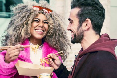 Farklı kültürlerden mutlu arkadaşlar dışarıda sokak yemeği yiyorlar, Yong modası geçmiş insanlar birlikte eğleniyorlar, içiyorlar ve gülüyorlar, şehir yaşam tarzı ve parti konsepti, siyah kız yüzüne odaklan.