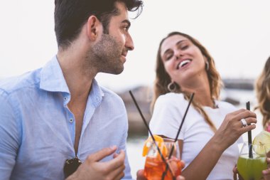 Bir grup arkadaş sahildeki büfede kokteyllerle kadeh kaldırıyor. Genç arkadaşlar dışarıda tezahürat yaparken eğleniyorlar. Ellerine odaklan. Mutluluk ve birliktelik yaşam tarzı konsepti.