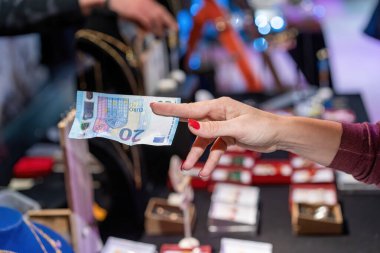 Paying cash: closeup of a woman hand paying with 20 euro banknote in a local market.