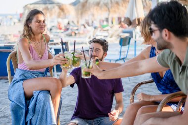 Yaz günbatımında sahilde bira içen iki genç çift. Gençlerin yaşam tarzı konsepti