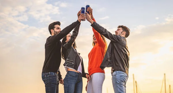 İki erkek ve iki kız dışarıda bira kutusuyla gülüp kadeh kaldırıyorlar. Tasasız gençlik dışarıda eğleniyor..