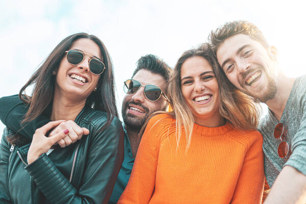 Portrait of 20s young friends having fun together and watching the camera. Outdoor shot at sunset time in the seaside