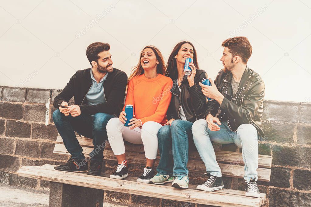 Two guys and two girls smiling and toasting with canned beers outdoor. Carefree youth having fun outdoors.
