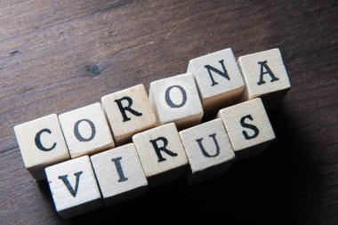 Tahta arka planda pul küpü harfleri olan Corona virüsü harfleri.