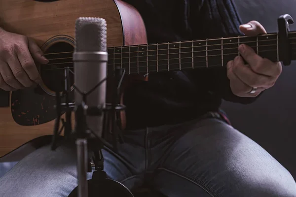 Musician recording his songs at home. Guitar player recording music with condenser microphone in a home studio.