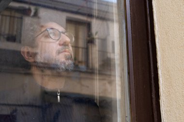 Orta yaşlı bir adam karantina, koronavirüs ve günlerce yaşayacağı geleceği düşünüyor. Evde kal, güvende kal..