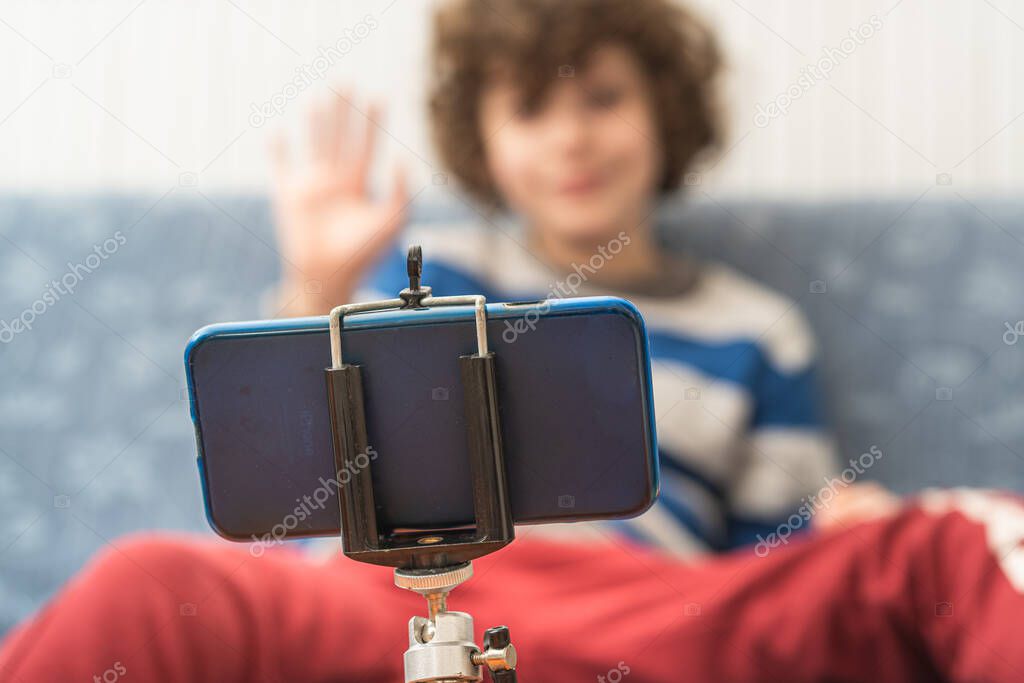 Children saluting parents or friends during an online video calling. People using technology safely at home during the coronavirus quarantine lockout. Focus on smartphone shallow depth of field.