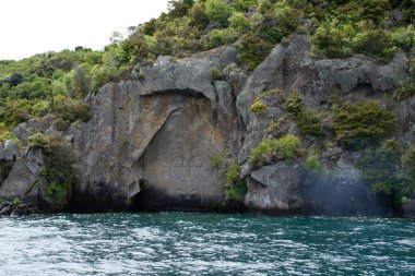Yeni Zelanda 'yı, Kuzey Adası' nı, Taupo 'yu dolaş. Büyük Taupo Gölü 'ndeki kayada oyulmuş Iconic Maori kayası manzarası. Popüler turistik ilgi / etkinlik.