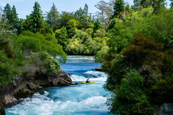 Travel New Zealand. Most popular tourist attraction Huka Falls at Lake Taupo, North Island. White and turquoise water, green forest on background. Beautiful landscape view. Active summer holidays.