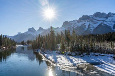 Kanada Peyzajı. Karla kaplı dağ manzarası, Bow Nehri ve kışın Üç Kız Kardeş manzarası. Kanada dağlarında güneşli güzel bir gün. Canmore, Alberta, Kanada.