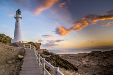 Gündoğumu renklerinde Castlepoint deniz fenerinin panoramik manzara manzarası, beyaz simge, Kuzey Adası, Yeni Zelanda 'da turist popülerliği / varış noktası. 