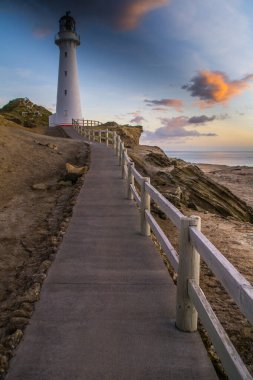 Gündoğumu renklerinde Castlepoint deniz fenerinin panoramik manzara manzarası, beyaz simge, Kuzey Adası, Yeni Zelanda 'da turist popülerliği / varış noktası. 