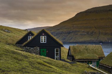 Vagar Adası 'nda çimen (çim) çatılı geleneksel tarihi ahşap ev / bina manzarası. Faroe Adaları 'nda (Danimarka) turist popülerliği)
