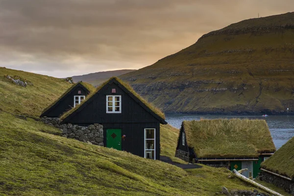 Vagar Adası 'nda çimen (çim) çatılı geleneksel tarihi ahşap ev / bina manzarası. Faroe Adaları 'nda (Danimarka) turist popülerliği)