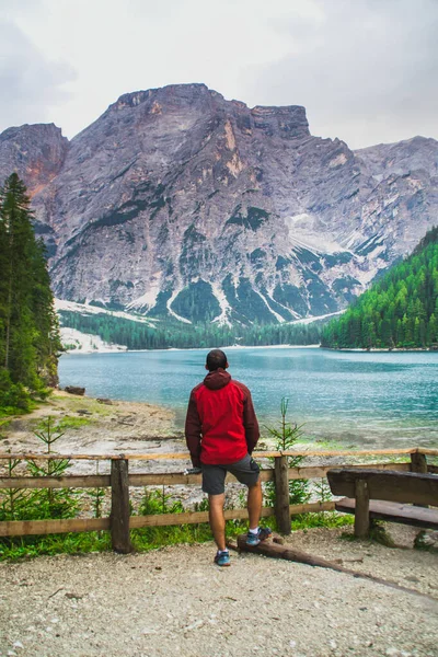 Güney Tyrol, İtalya 'da romantik Lago di Braies (Pragser Wildsee) manzaralı kırmızı yağmurluk giyen turist.