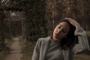 Kız ormanda yürüyor, güneşi hissediyor ve gözlerini kapıyor.