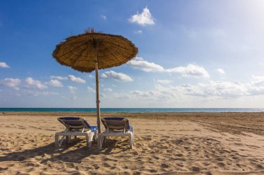 Plaj şemsiye ve şezlonglar, mavi gökyüzü ile. Vacat güneşli günde