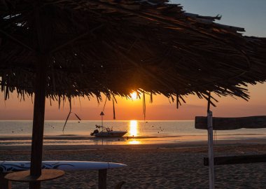 Rivazzurra 'da (Rimini / İtalya) güzel okyanus gündoğumu sırasında şafak vakti plajda motorlu tekne