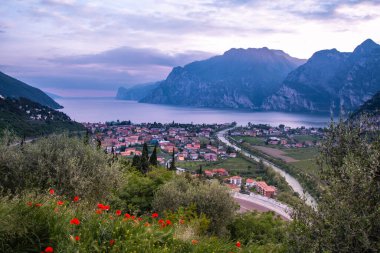 Kuzey Lago di Garda (Garda Gölü), Trentino, İtalya 'da Torbole' un dramatik bulutlu gökyüzü ile panoramik akşam gün batımı manzarası; Corona Virüs Salgını 'nın boş otel odaları yüzünden turizmde yaşanan mali kayıp