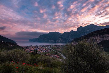 Kuzey Lago di Garda (Garda Gölü), Trentino, İtalya 'da Torbole' un dramatik bulutlu gökyüzü ile panoramik akşam gün batımı manzarası; Corona Virüs Salgını 'nın boş otel odaları yüzünden turizmde yaşanan mali kayıp