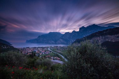 Kuzey Lago di Garda (Garda Gölü), Trentino, İtalya 'da Torbole' un dramatik bulutlu gökyüzü ile panoramik akşam gün batımı manzarası; Corona Virüs Salgını 'nın boş otel odaları yüzünden turizmde yaşanan mali kayıp
