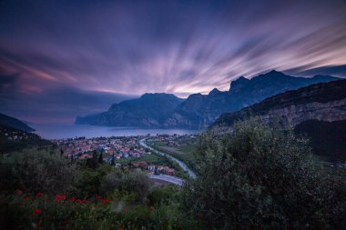 panoramic evening sunset view with dramatic cloudy sky of Torbole at northern Lago di Garda (Lake Garda), Trentino, Italy; financial loss in tourism due to empty hotel rooms for Corona Virus pandemic clipart
