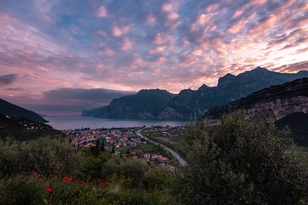 Kuzey Lago di Garda (Garda Gölü), Trentino, İtalya 'da Torbole' un dramatik bulutlu gökyüzü ile panoramik akşam gün batımı manzarası; Corona Virüs Salgını 'nın boş otel odaları yüzünden turizmde yaşanan mali kayıp