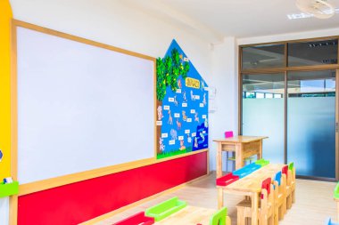 Anaokulundaki masalar, sandalyeler ve beyaz tahta. Ve