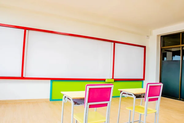 Secretárias, cadeiras e prancha branca na sala de aula do jardim de infância . — Fotografia de Stock