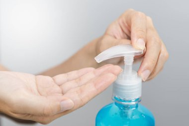 Kadının eli mikropları, virüsleri, koronavirüsü ve Covid-19 'u önlemek için dezenfektan jel şişesine basıyor..