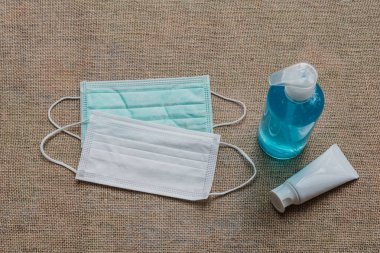 Şişedeki mavi dezenfektan ve mikropları, virüsleri, bakterileri ve Covid-19 'u önlemek için beyaz tüp jeli. Kenevir kumaşındaki virüsleri korumak için kullanılan alkol jeli şişesi..